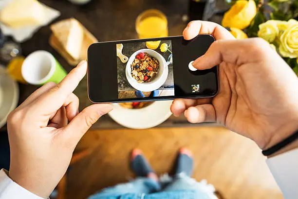 Photo of Teenage Girl photographing breakfast with smartphone