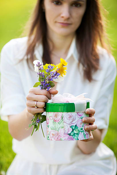 istock Young girl holding box with present and flowers 533904227