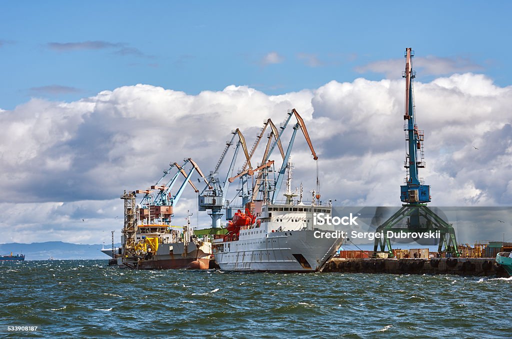 Cargo ship docked pier port Cargo ship docked pier, crane, port, sea and cloudy blue sky 2015 Stock Photo