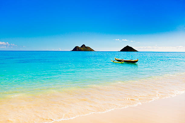 Outrigger Canoe on the Beach of Oahu Hawaii An outrigger canoe floating in aqua blue sea of Oahu Hawaii. outrigger stock pictures, royalty-free photos & images