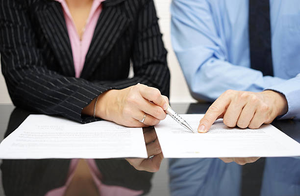 businessman and businesswoman are pointing to .article of the treaty stock photo