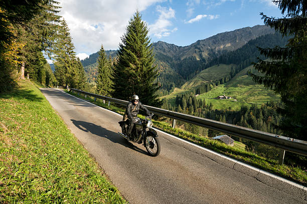 retro style biker driving with vintage motorcycle Laterns, Vorarlberg, Austria - October 4, 2014: motorcyclist driving with old norton bike downwards from Furka pass norton brand name stock pictures, royalty-free photos & images