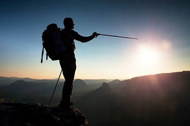 Photo of Silhouette  with sun in the frame. Tourist guide in mountains