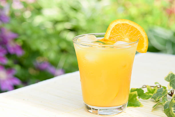 a glass of fresh orange juice with slice of orange