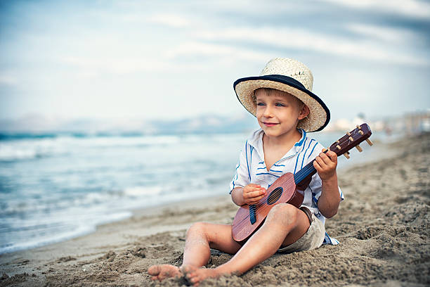 istock Little boy playing little guitar on the beach. 533916958