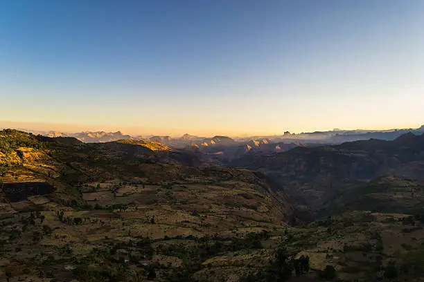 Wide angle view from the Simien Mountains National Park on the misty valleys and the glowing highlands of the Tigray region, hit by the first golden sunlight. Northern Ethiopia, East Africa.