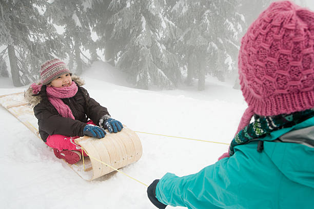 Mother and the little girl are playing in winter park, mother and cute girl