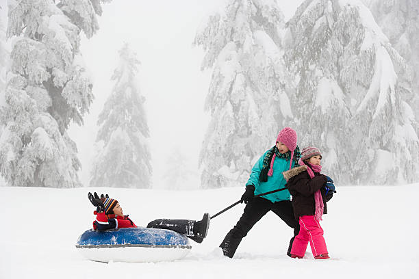 garçon sur canot toboggan - child winter snow asian ethnicity photos et images de collection