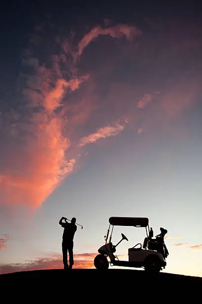 Photo of Male Caucasian Golfer Swinging A Golf Club with Cart