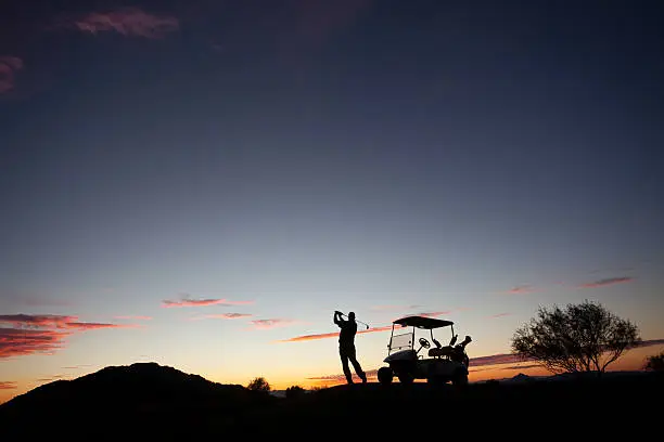 Photo of Male Caucasian Golfer Swinging A Golf Club with Cart