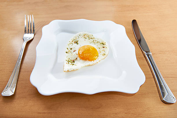 istock Fried eggs in heart shape on white plate and cutlery 533959575
