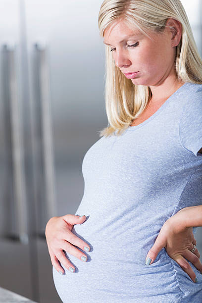 беременная женщина с руку на живот - human pregnancy rubbing looking down abdomen стоковые фото и изображения