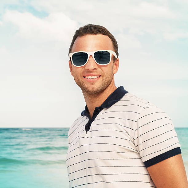 istock Young smiling man in white sunglasses on sea coast 533963271