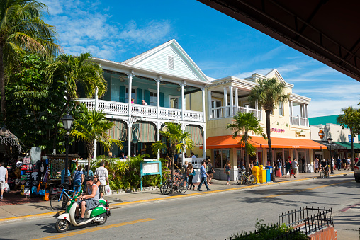Key West, Florida, USA - January 17, 2015: Pedestrians as well as two tourists riding scooters enjoy a warm January day on Duval Street in Key West, Florida
