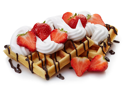 Belgian waffles with whipped cream, strawberries and chocolate sauce isolated on white background