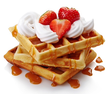 Belgian waffles with whipped cream, strawberries and caramel sauce  isolated on white background