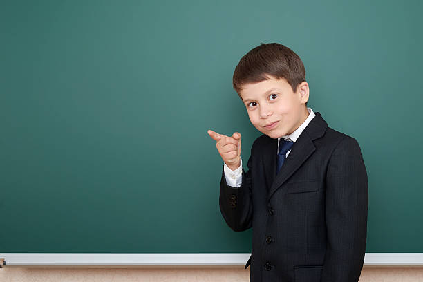 istock school boy show finger up gesture, point on green chalkboard 533974642