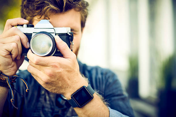 istock Trendy man adjusting camera lens while photographing 533975110