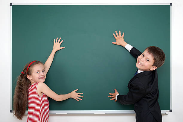 istock school boy and girl child show frame on empty chalkboard 533975726