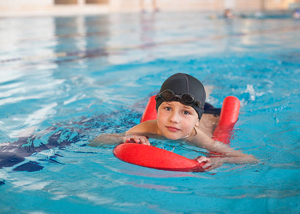 istock boy learn to swim with  red foam noodle in pool 533977224