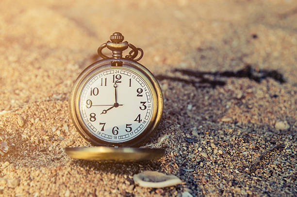 istock vintage pocket watch on sand beach background 533978562