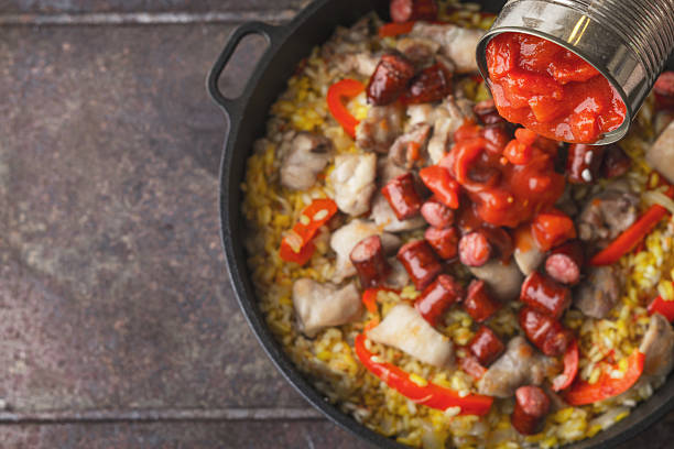 adición de tomates picados en la sartén con paella de cocción vista superior - fried onion roasted chopped fotografías e imágenes de stock