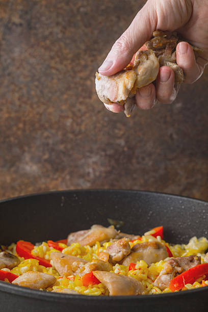 istock Adding chicken in  pan with rice and bell pepper vertical 533982624