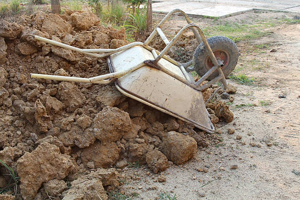Old rusty wheelbarrow upside down on a heap of soil in a building site, construction area,