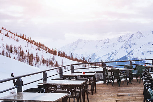 Balcony with table and chairs overlooking the snow-capped mountains of the Zell am See ski resort in Austria. Sunny winter day, vacation in the Alps. Relaxing horizontal photo without people