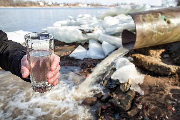 hombre se encuentra con un vaso lleno de agua de alcantarillado - water flowing water pouring ice fotografías e imágenes de stock