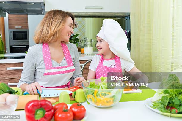 Happy Mother And Daughter Cooking A Salad Stock Photo - Download Image Now - 2015, Adult, Apron