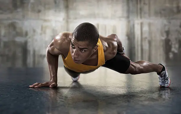 Photo of Sport. Young athletic man doing push-ups.