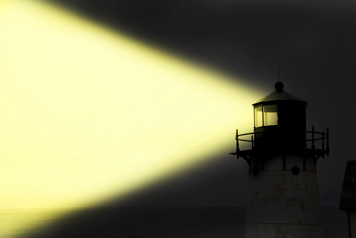 Light house shining yellow light at night with copy space.