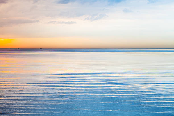 istock Still blue sea water under colorful sky 533997768