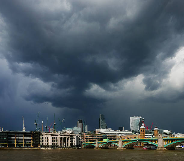 Threatening dark clouds over London's financial district. Buildings in sunshine.