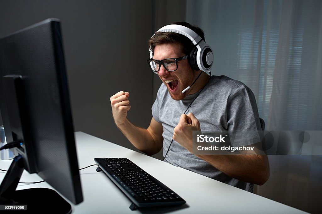 Homme au casque jouant ordinateur de jeux vidéo à la maison - Photo de Joueur de jeux informatiques libre de droits