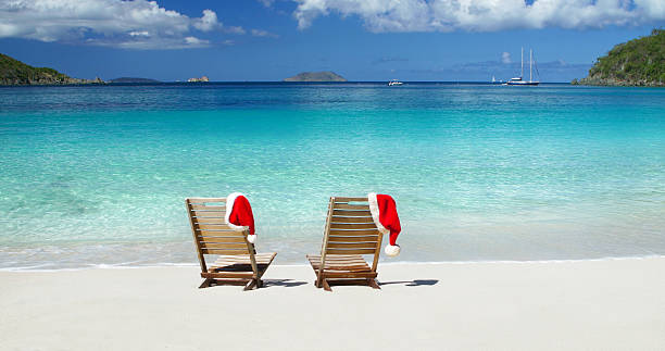 two teak chairs with Christmas hats at a Caribbean beach two empty teak chairs with Christmas hats at a beach in St.John, US Virign Islands st john's plant stock pictures, royalty-free photos & images