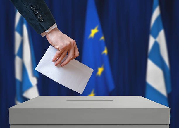 istock Election in Greece. Voter holds envelope above vote ball 534001126