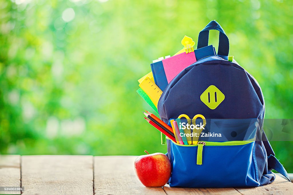 Full School backpack with apple on wooden and nature background. Full School backpack with apple on wooden and nature background Back to School Stock Photo