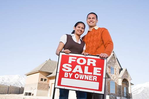 Portrait of a couple hold a for sale sign