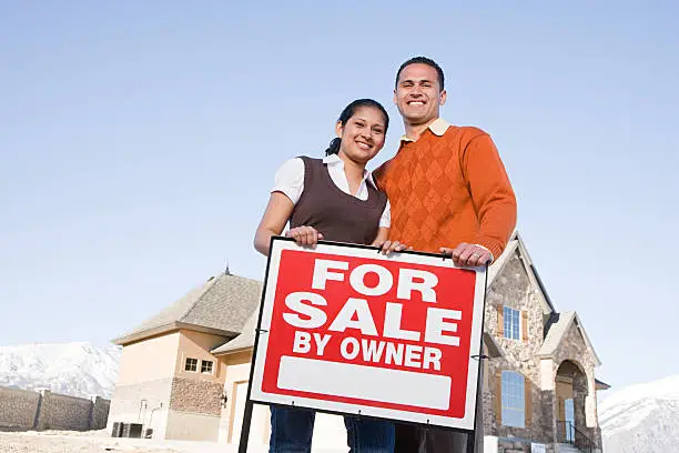 Photo of Portrait of a couple hold a for sale sign