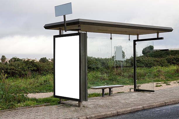 Rural bus stop with blank billboard Bus stop in a rural setting with a large blank billboard on the side of the shelter. Grey, rainy day and vegetation in the background. bus shelter stock pictures, royalty-free photos & images