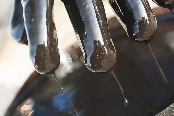 istock Fingers in glove with oil drops into barrel 534002865