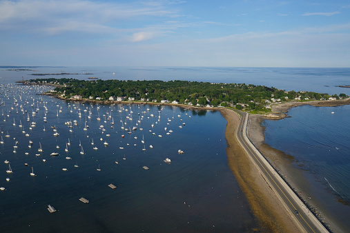 An aerial view of the causeway and harbor alongside Marblehead Neck, Massachusetts. The harbor is filled with pleasure watercraft during summer.