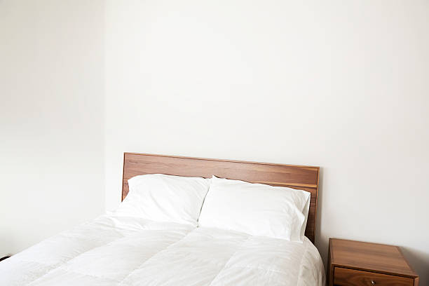 cama de casal com um edredom e travesseiros e mesa de cabeceira - double bed night table headboard bed - fotografias e filmes do acervo