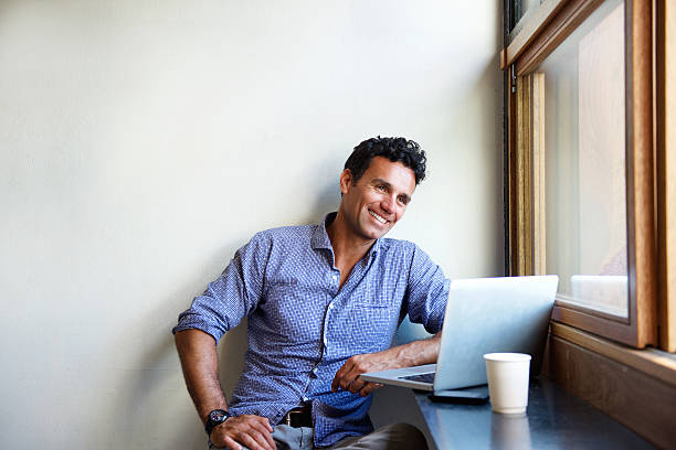 Mandsome modern man smiling with laptop at cafe