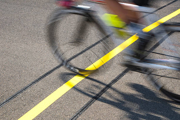 Blurred cyclist, due to speed, reaching the finishing line on a race. The action focus on the goal line