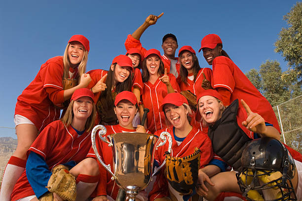 istock Softball Team And Coach With Trophy Celebrating Against Sky 534025977