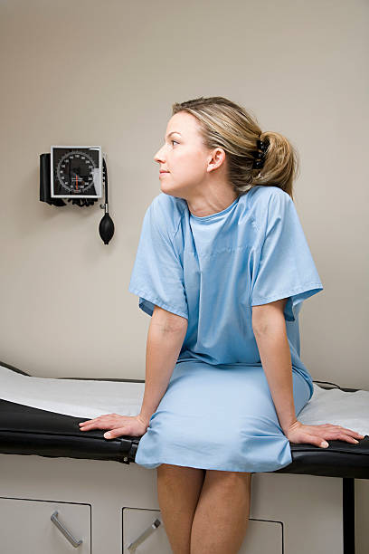 mujer esperando en el sofá de la sala de tratamiento - examination gown fotografías e imágenes de stock