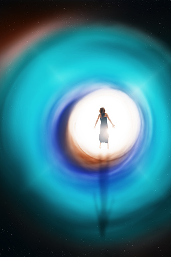 A conceptual image of the figure of a woman floating into the light at the end of a colorful tunnel.